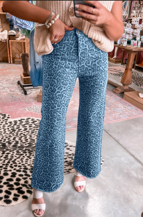 Person wearing blue leopard-print pants and open-toe heels, standing in a store.