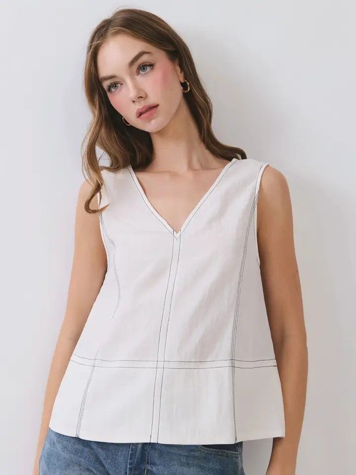 Woman in a white sleeveless V-neck top against a light background