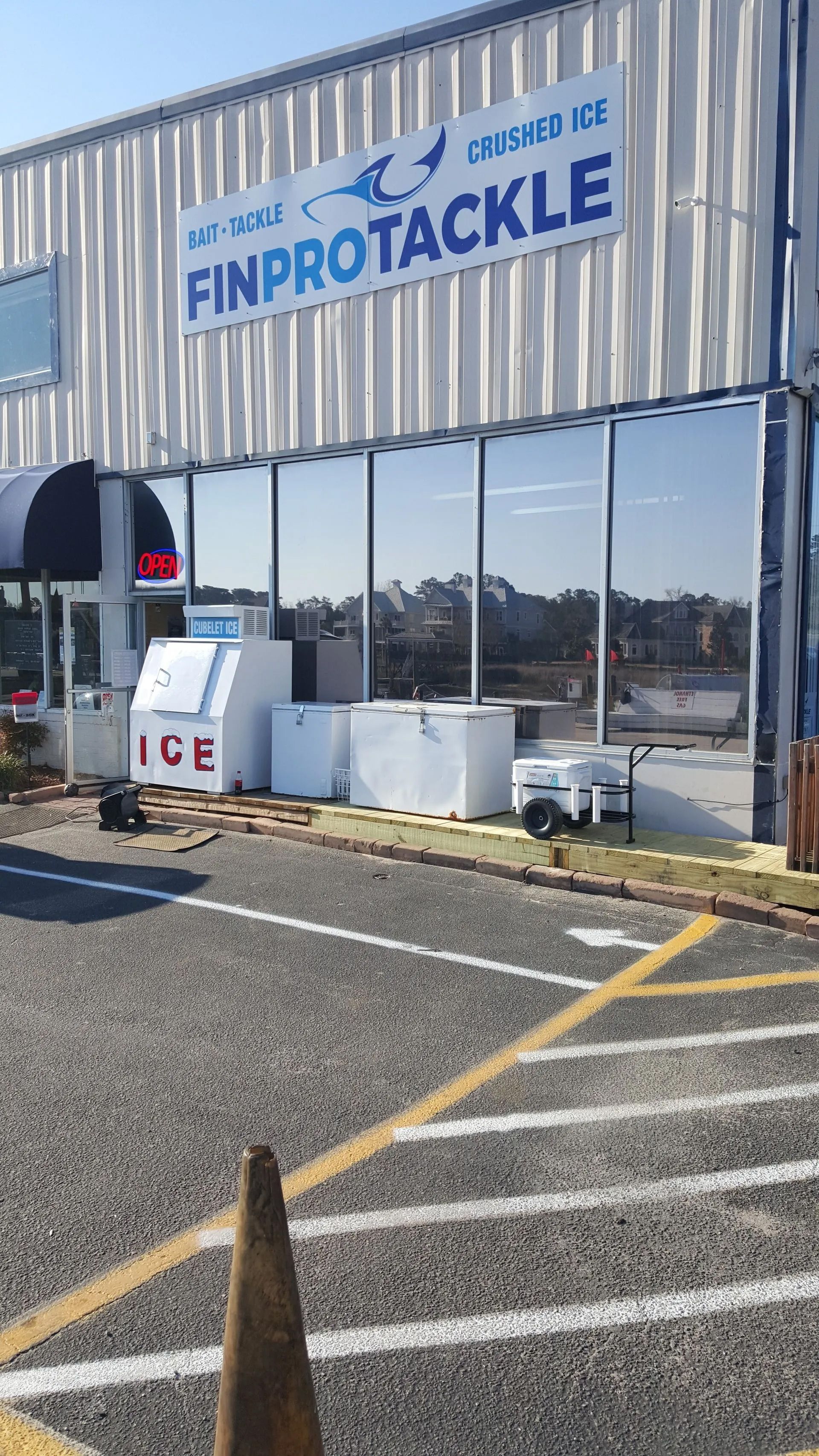 FinPro Tackle storefront with ice machines. Blue signage, reflective windows, and a gravel parking lot.