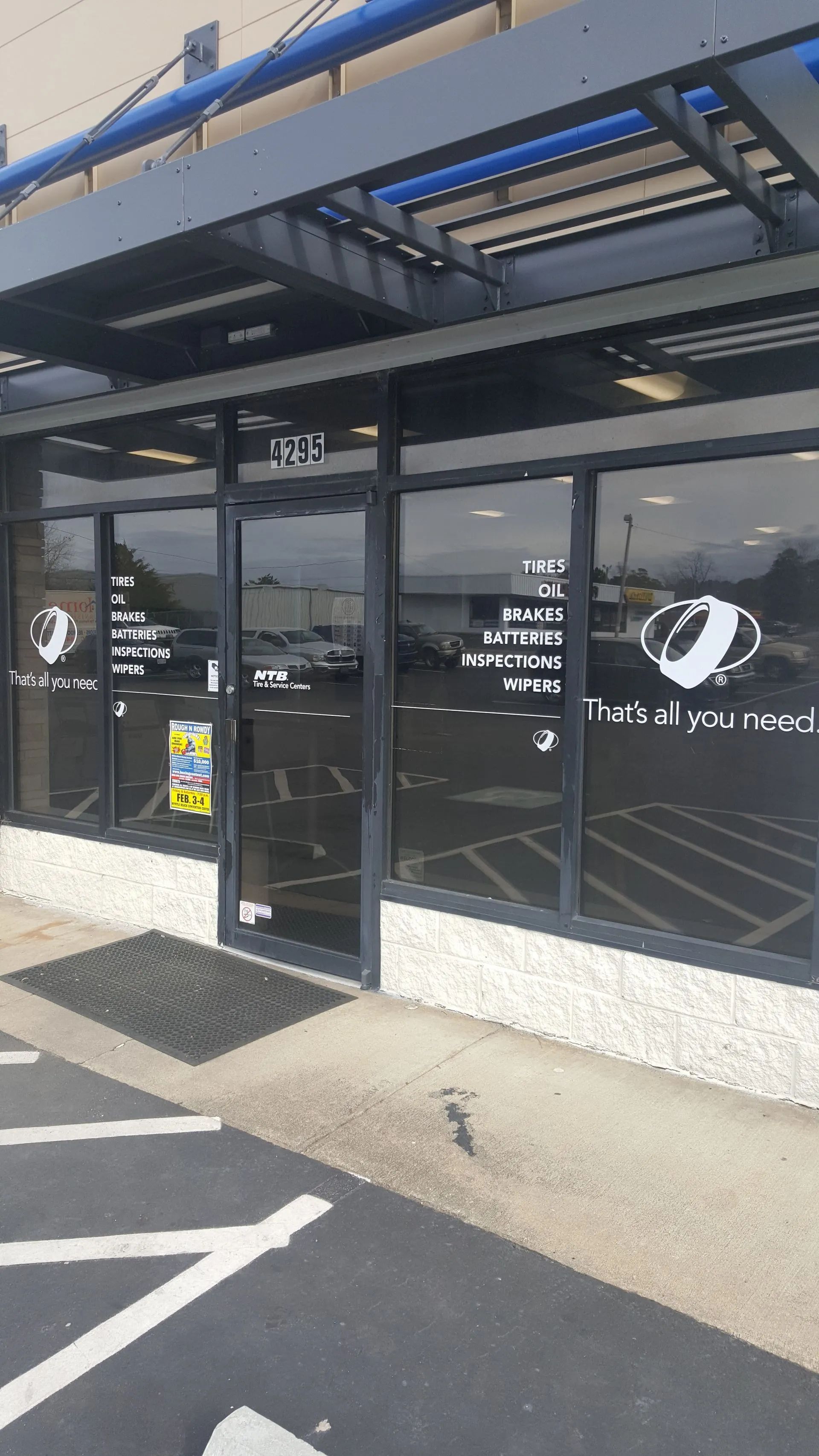 Exterior view of a business with glass windows and door, a black awning, and the address 153B visible.