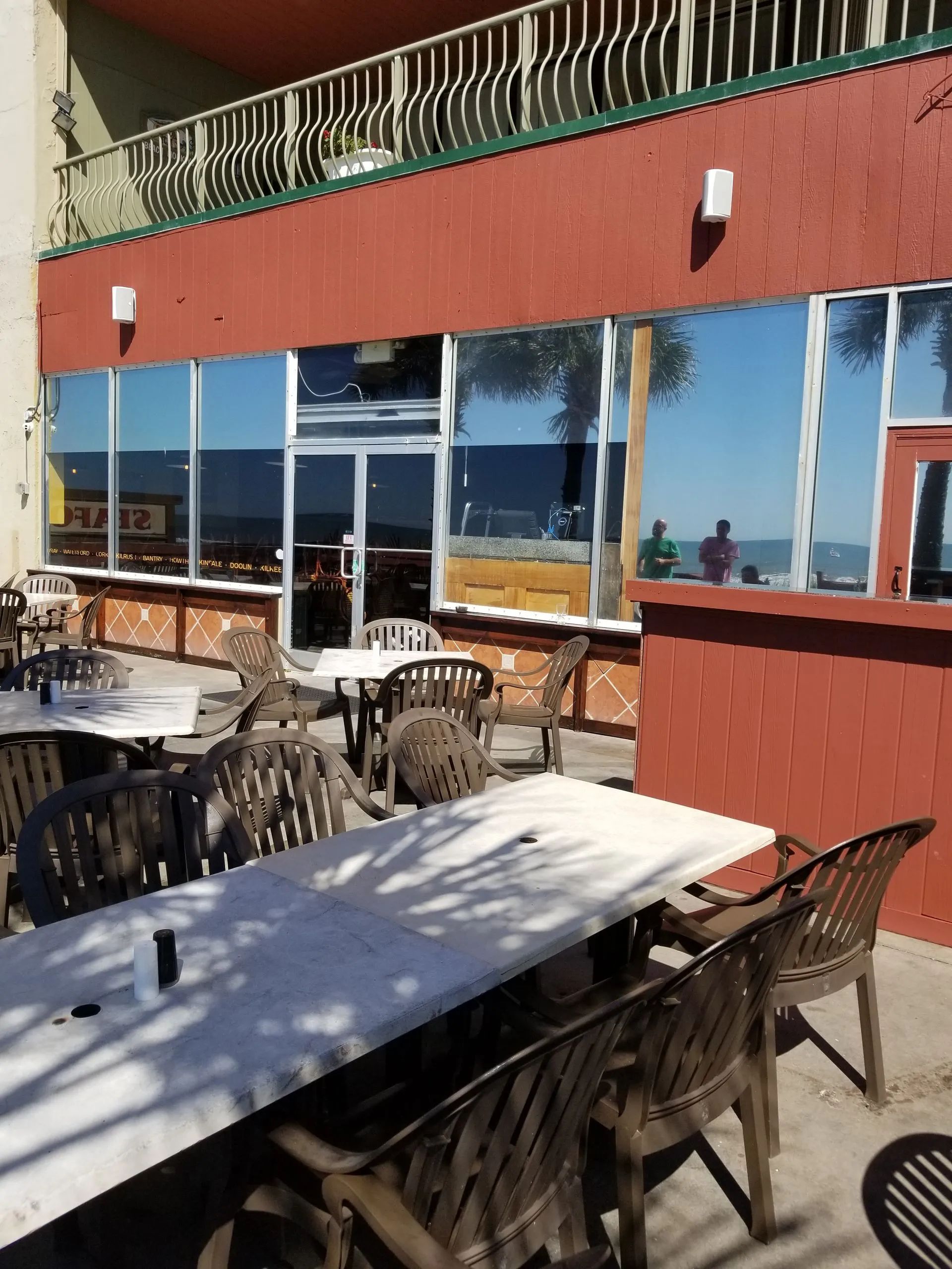 Outdoor restaurant seating with tables and chairs in front of a building with reflective windows.