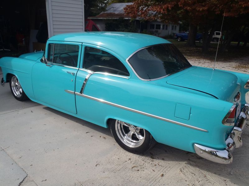 Turquoise 1955 Chevrolet classic car parked in a driveway. Chrome accents and wheels.