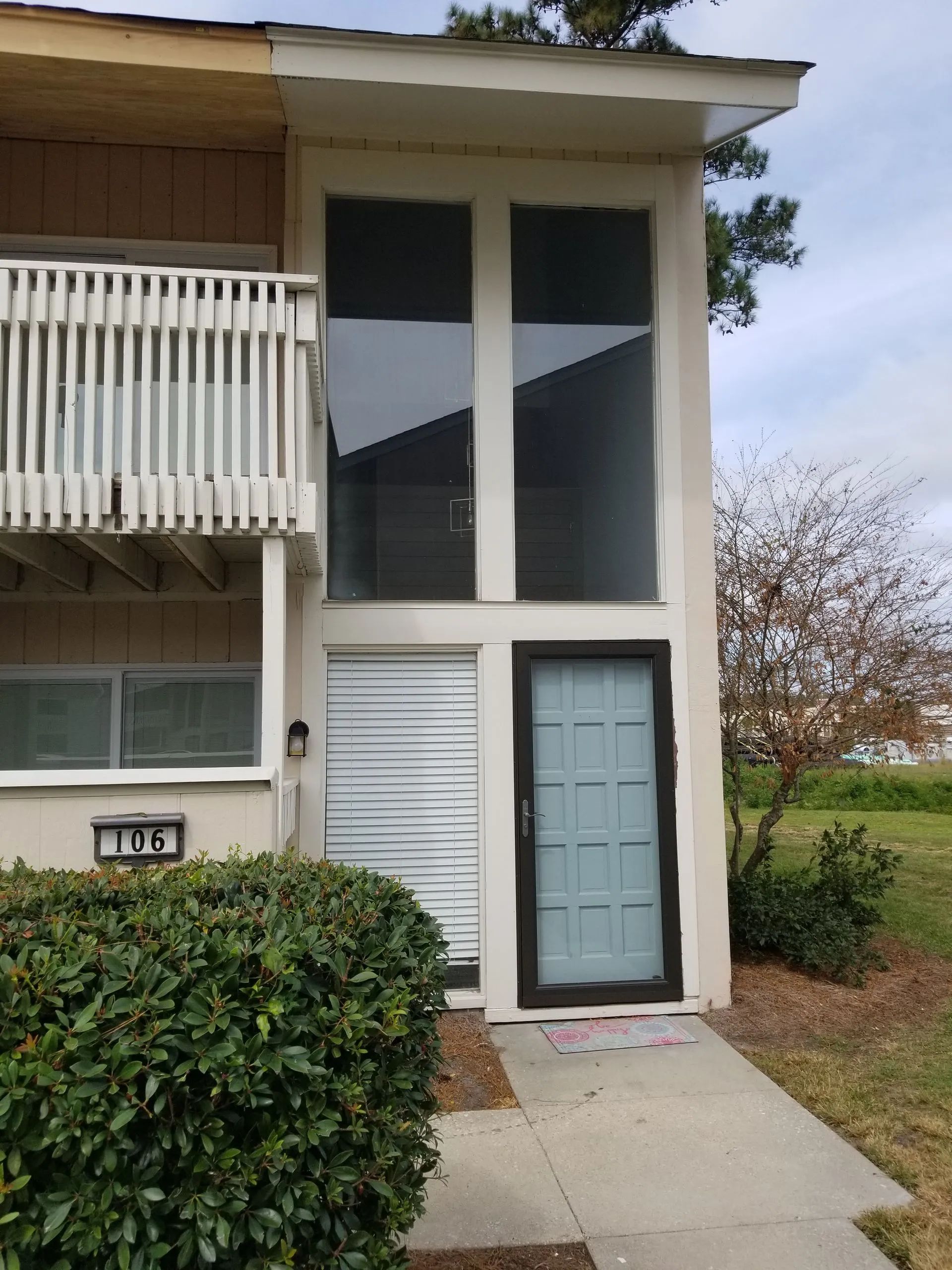 Exterior of a townhouse unit with a light blue door, large windows, and a balcony.