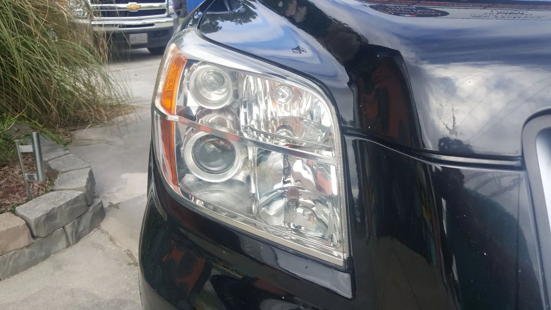 Black car headlight close-up, with two circular lights and one rectangular.
