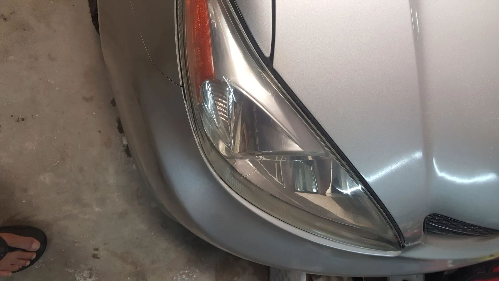 Silver car front with headlight and orange indicator lit.