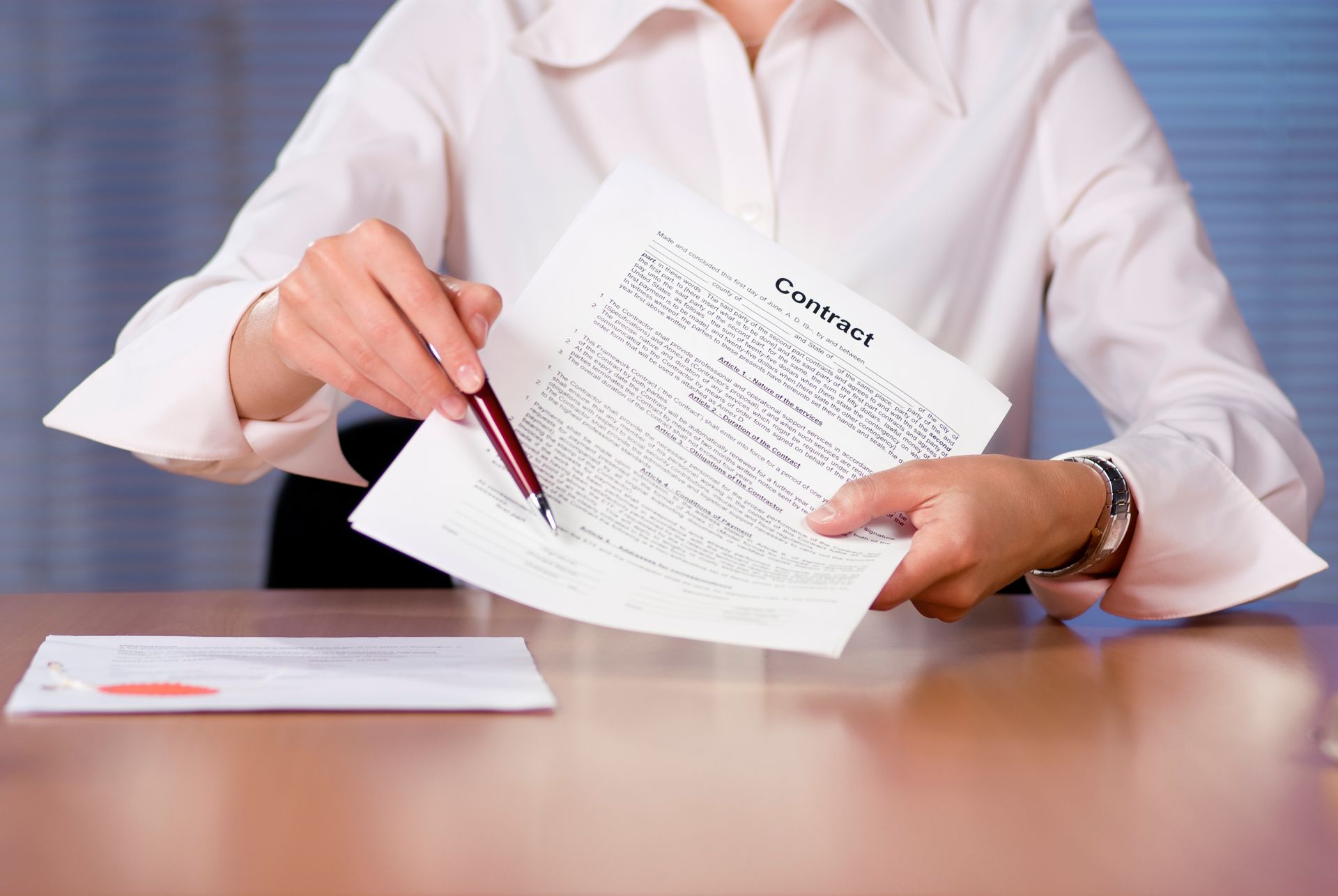 Person in a white shirt reviewing and signing a document at a desk