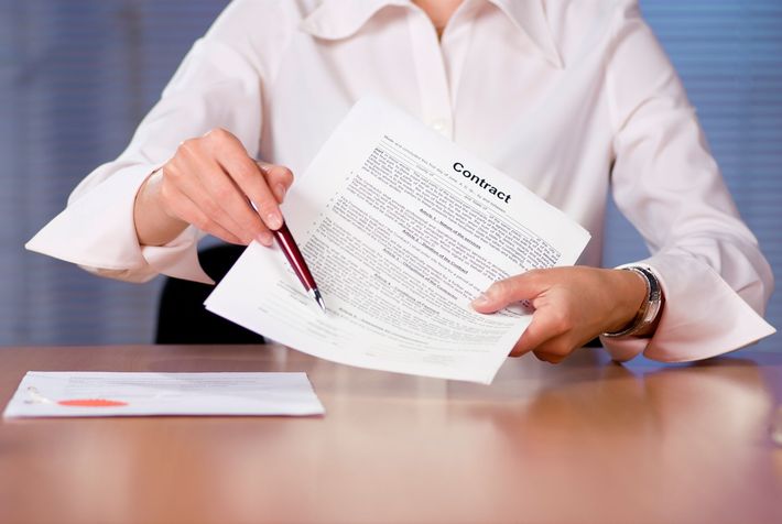 Person in a white shirt reviewing and signing a document at a desk