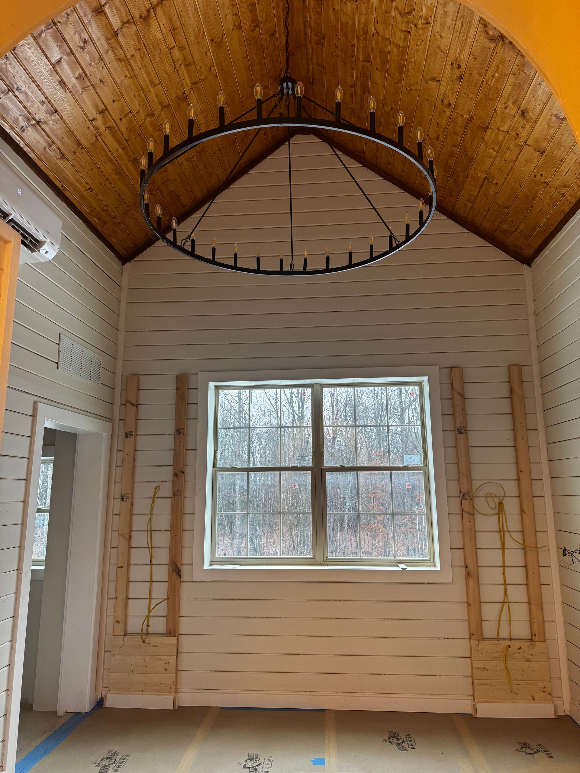A room with a large window and a chandelier hanging from the ceiling