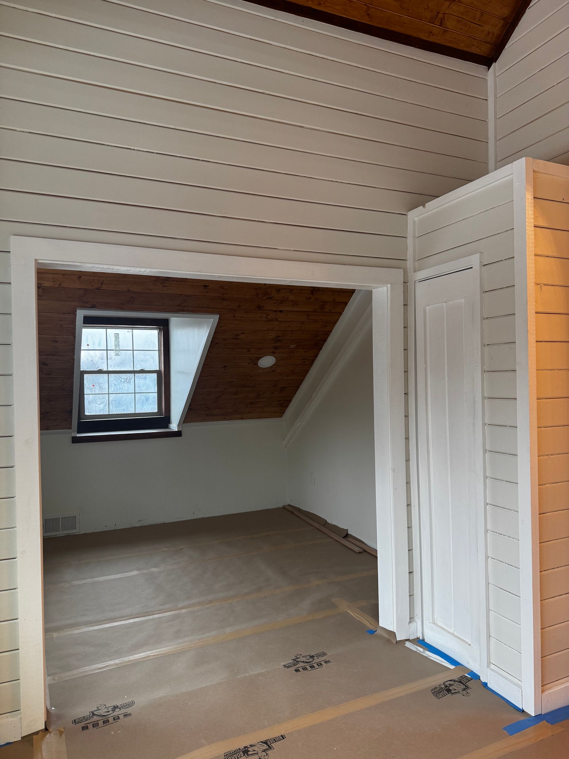 An empty room with a window and a wooden ceiling