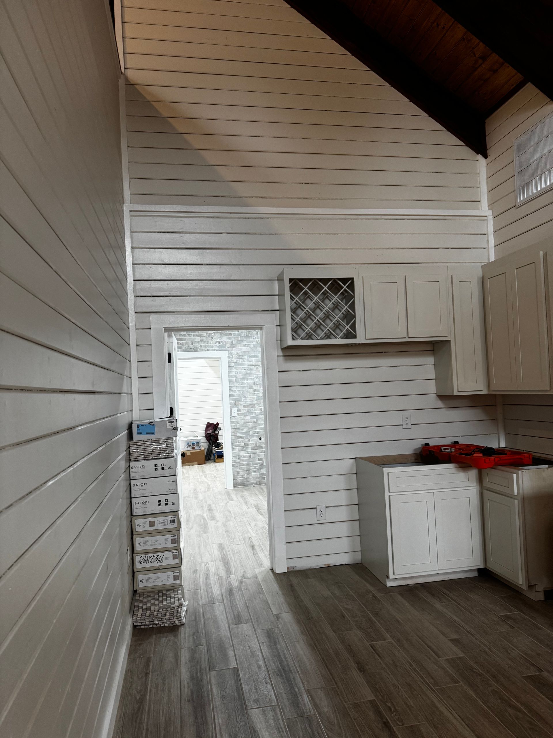 A kitchen with a vaulted ceiling and white cabinets