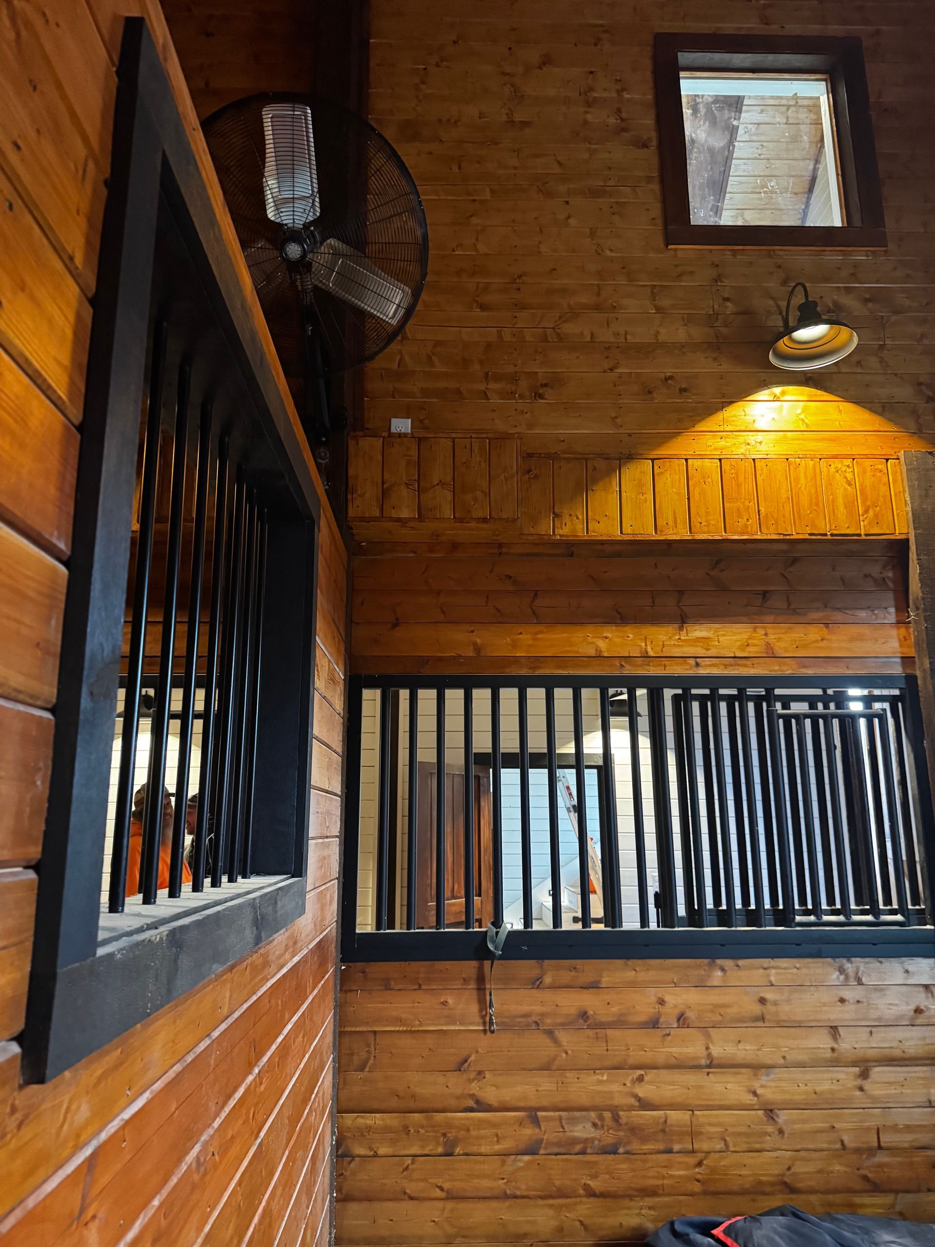 A wooden stable with a window and a fan