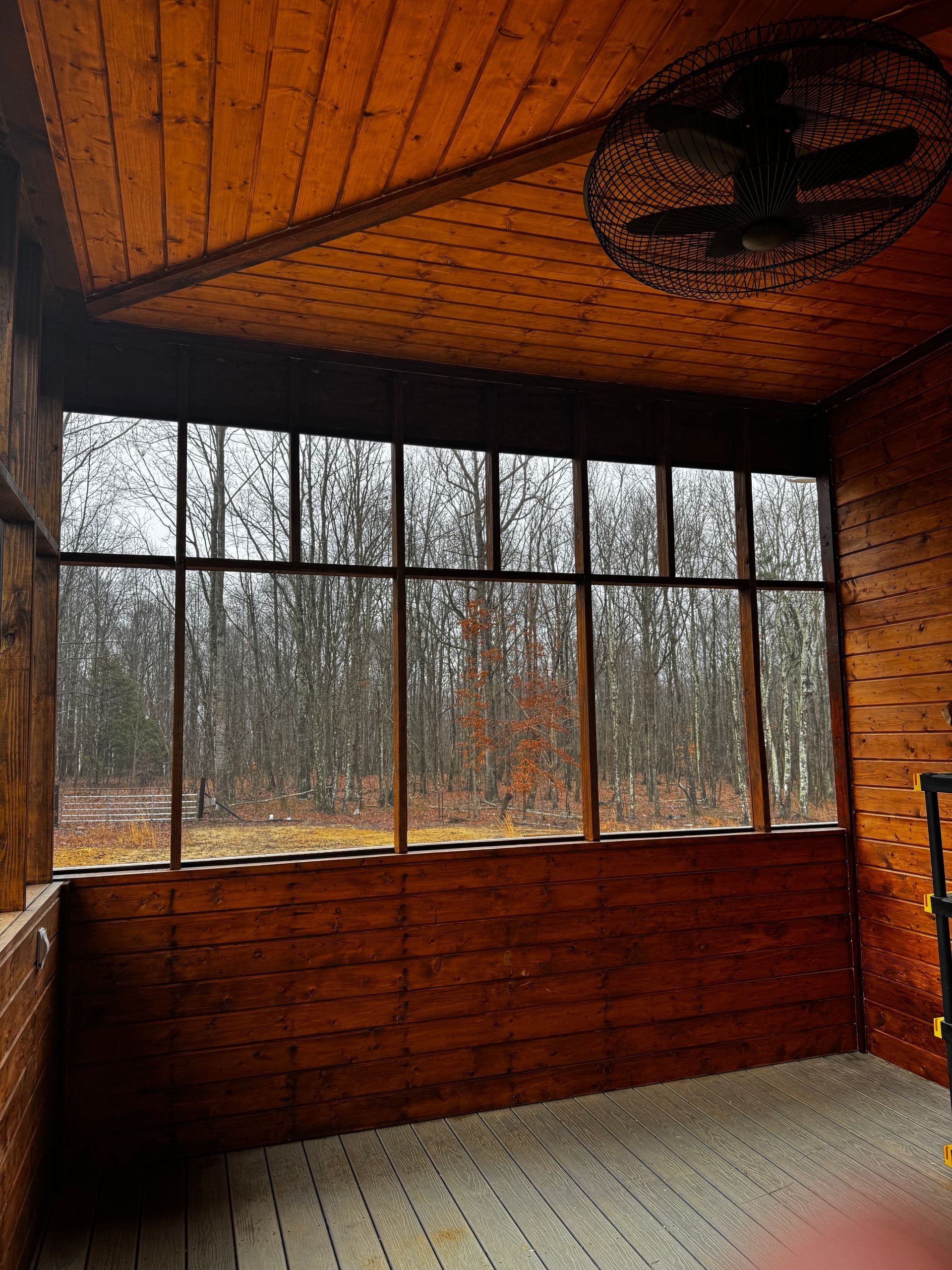 A wooden room with a lot of windows and a fan on the ceiling.