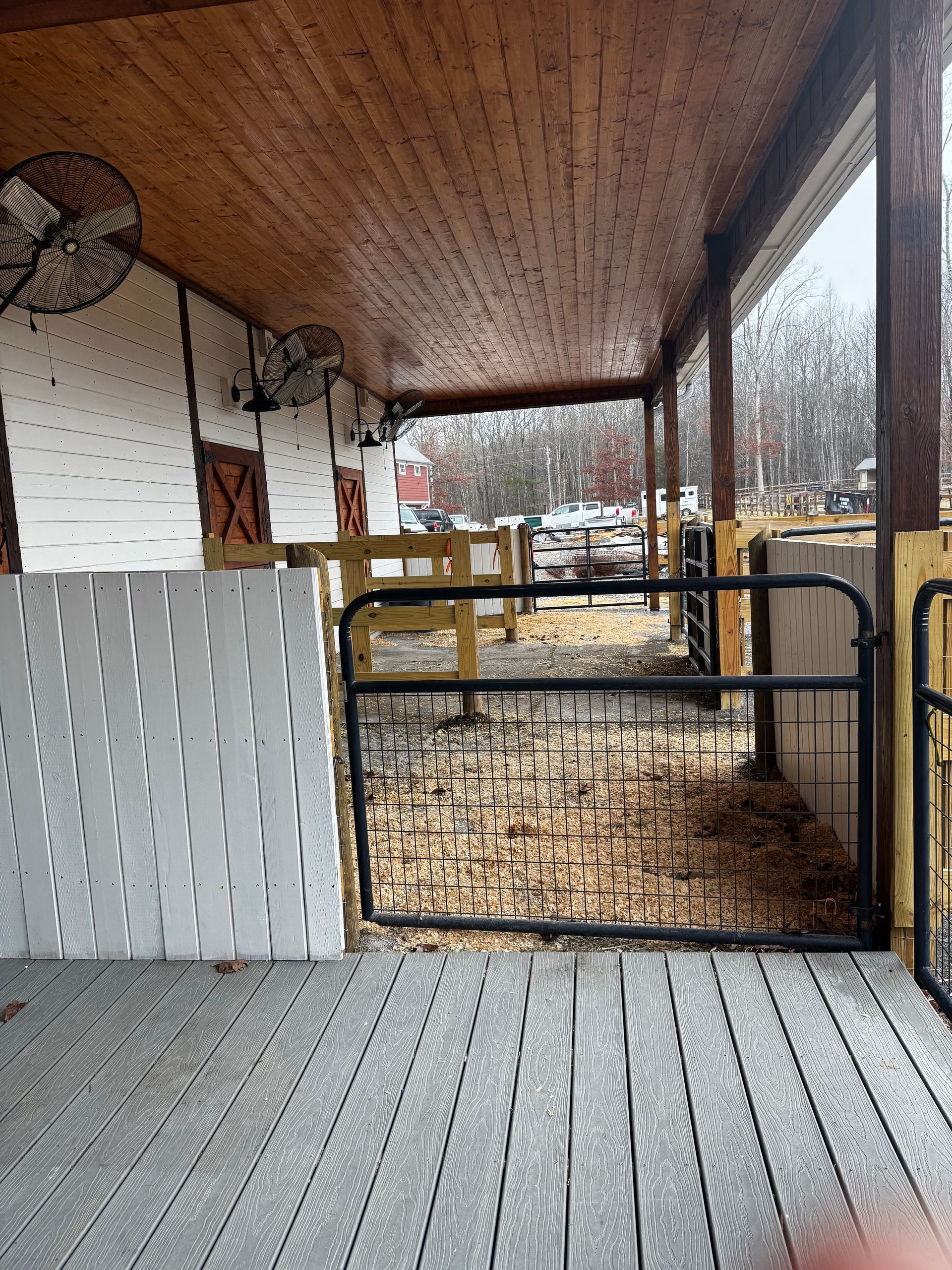 A horse stable with a wooden roof and a black gate.