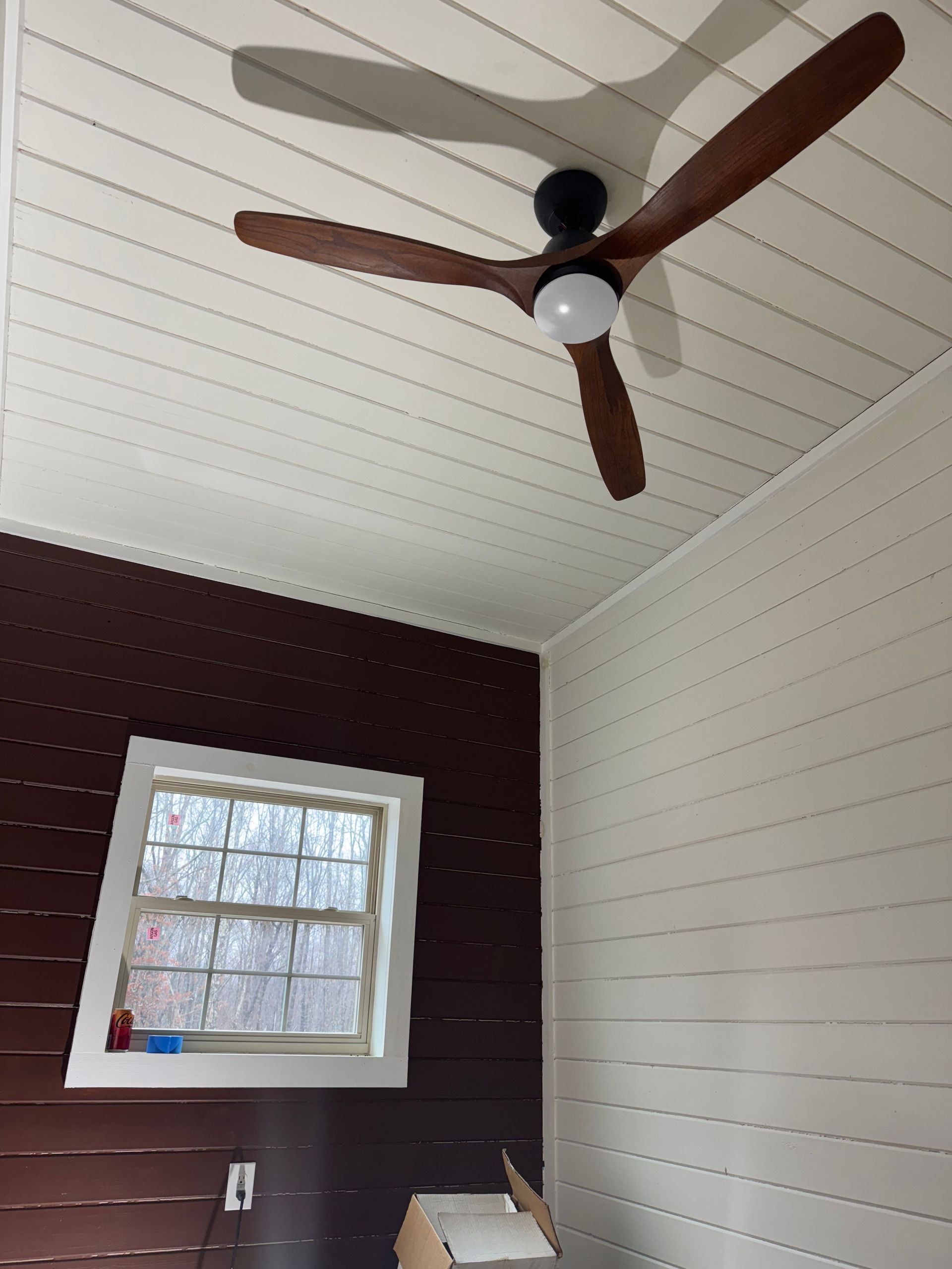 A ceiling fan is hanging from the ceiling of a room with a window.