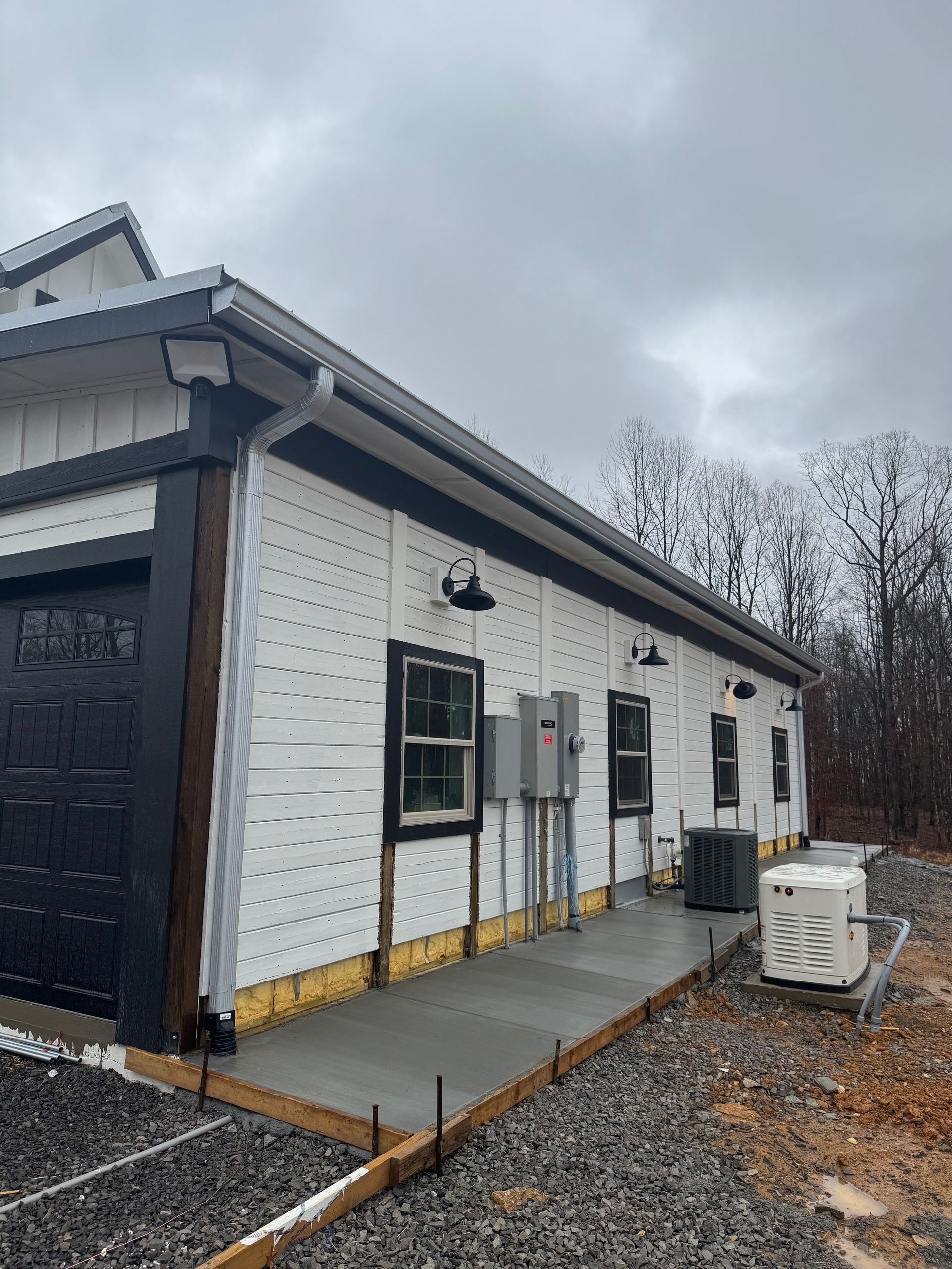 A white house with a black garage door is being built.