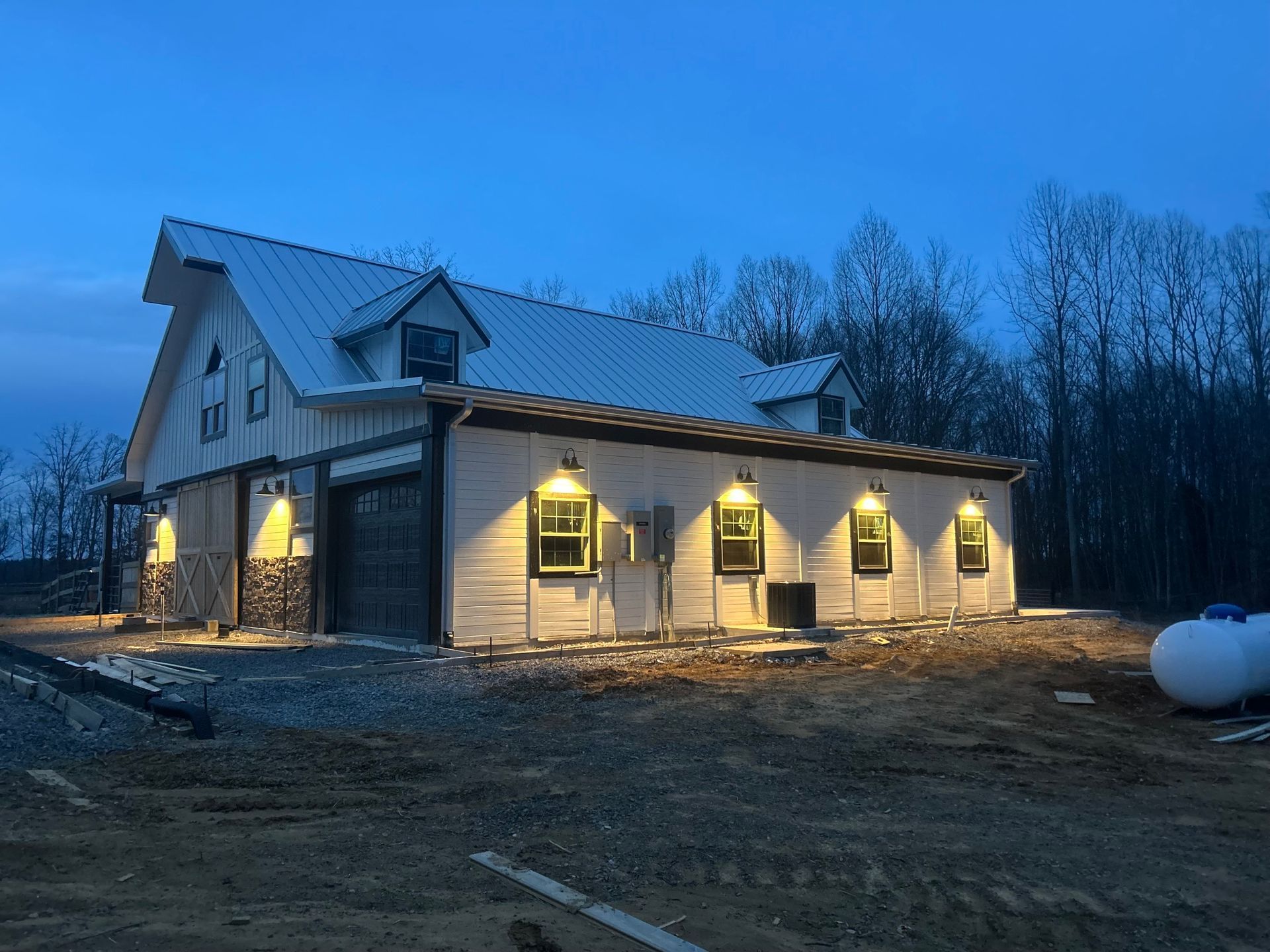 A large white house with a metal roof is lit up at night.