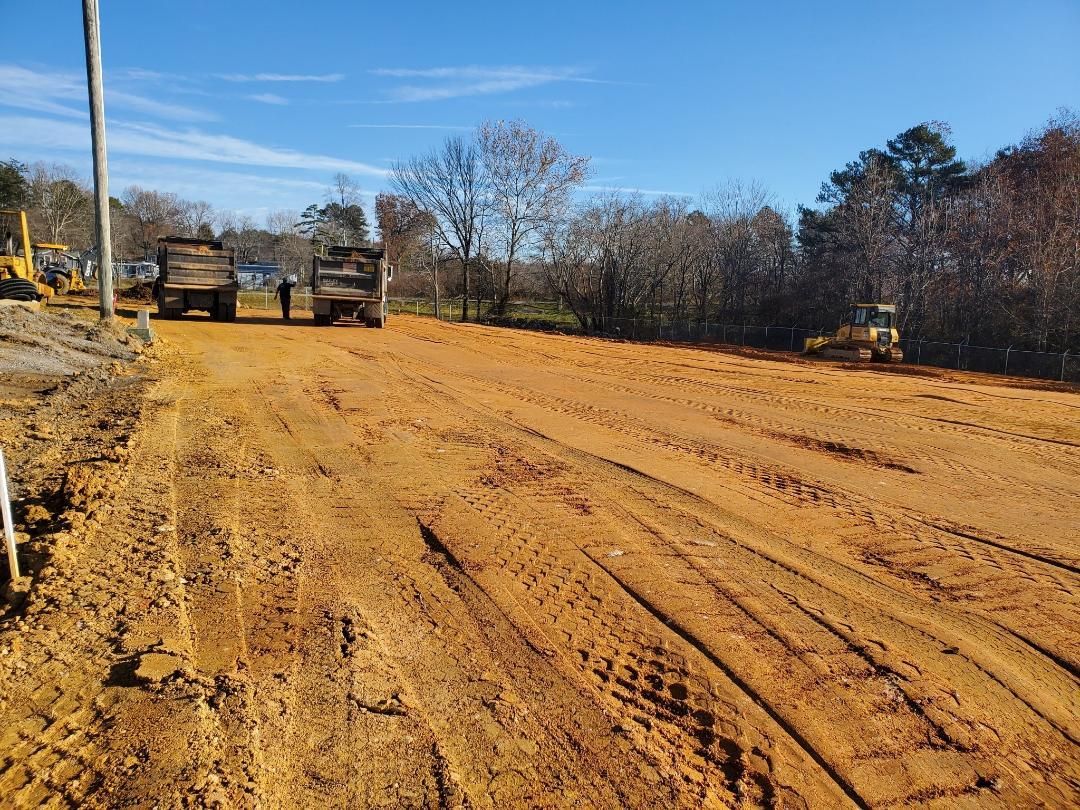 A truck is driving down a dirt road next to a bulldozer.