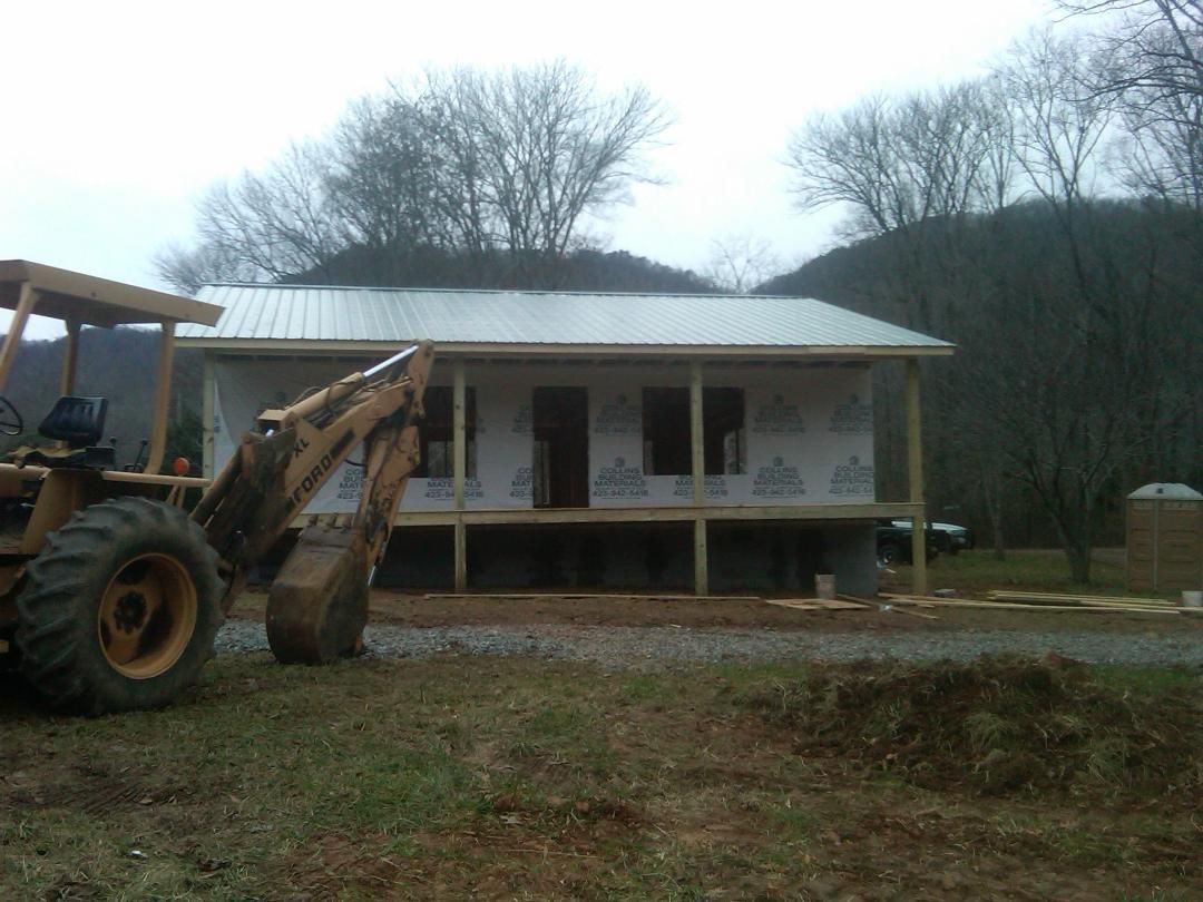 A tractor is parked in front of a house under construction.