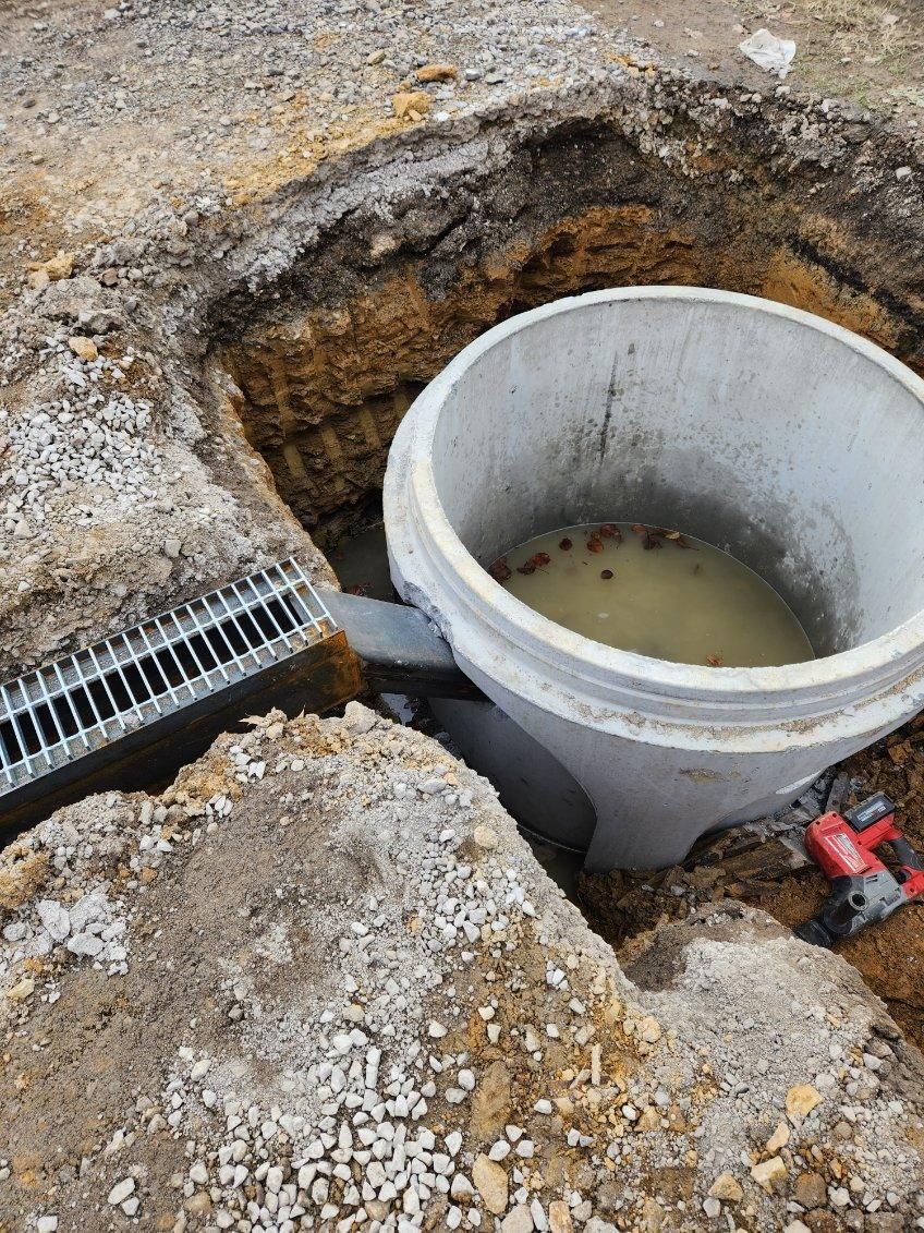 A large concrete bucket filled with water is sitting in a hole in the ground.