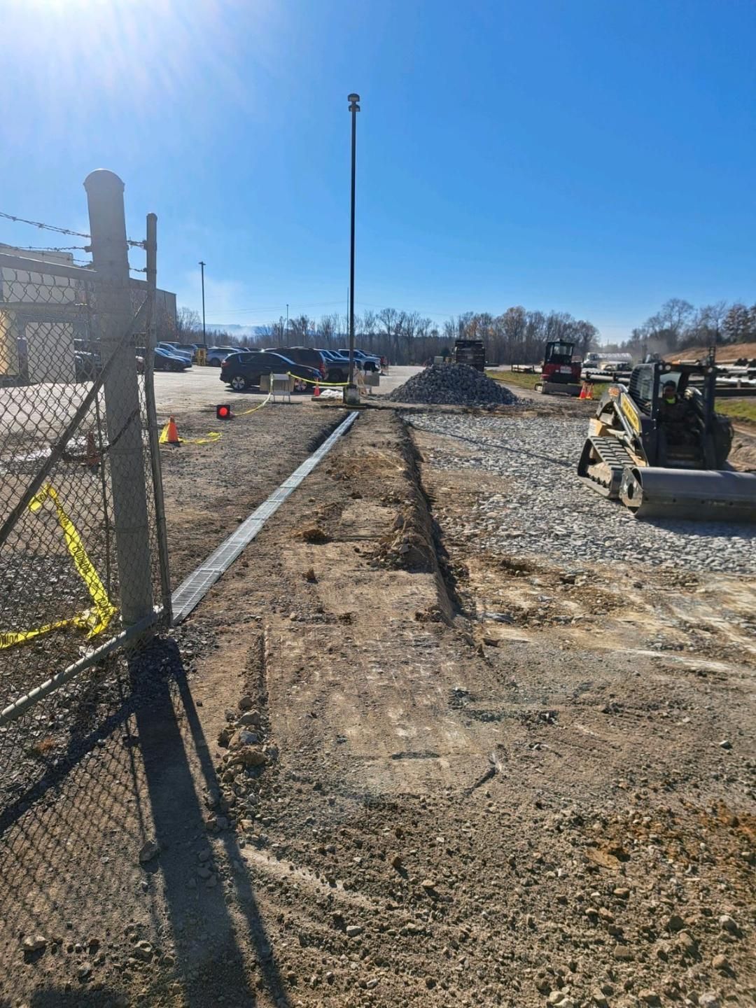 A construction site with a chain link fence and a bulldozer in the background.