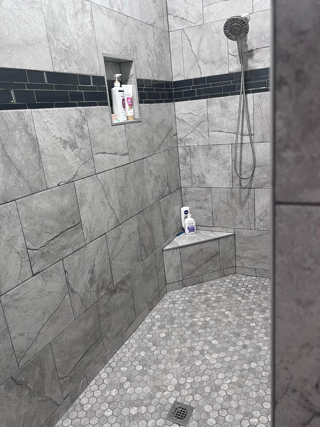 A shower with a corner shelf and a shower head.