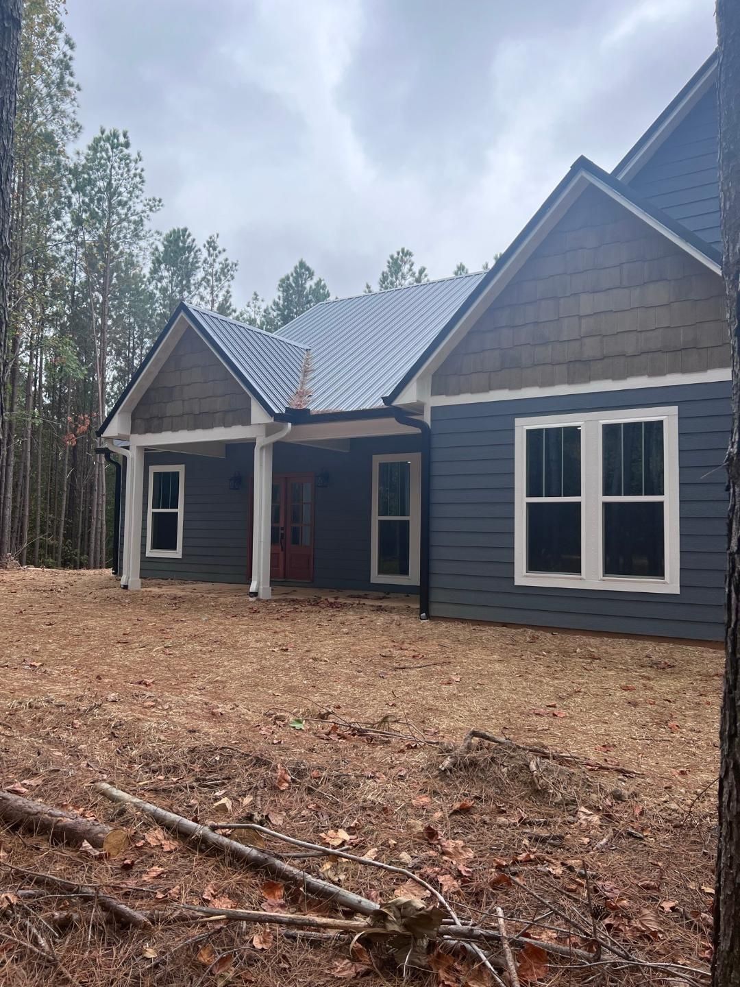 A house is sitting in the middle of a field surrounded by trees.