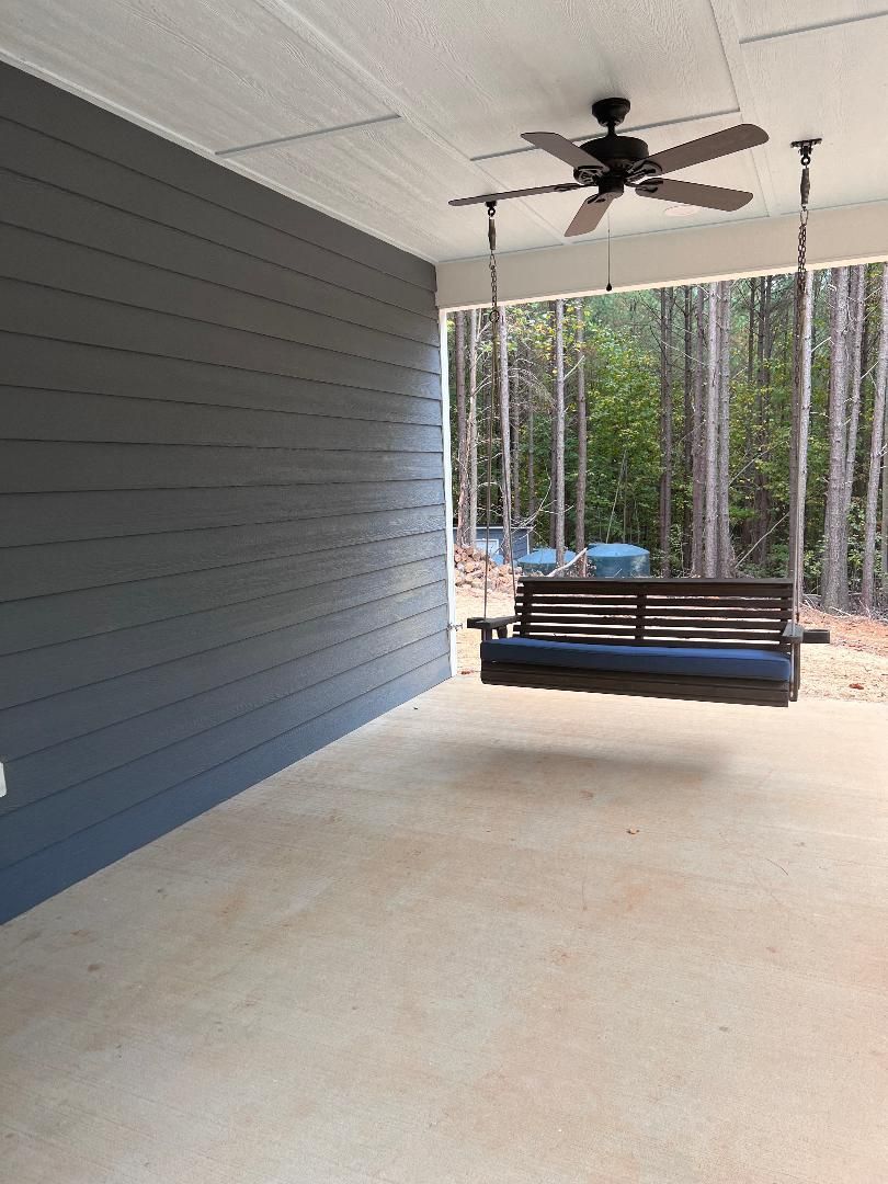 A porch with a swing and a ceiling fan.