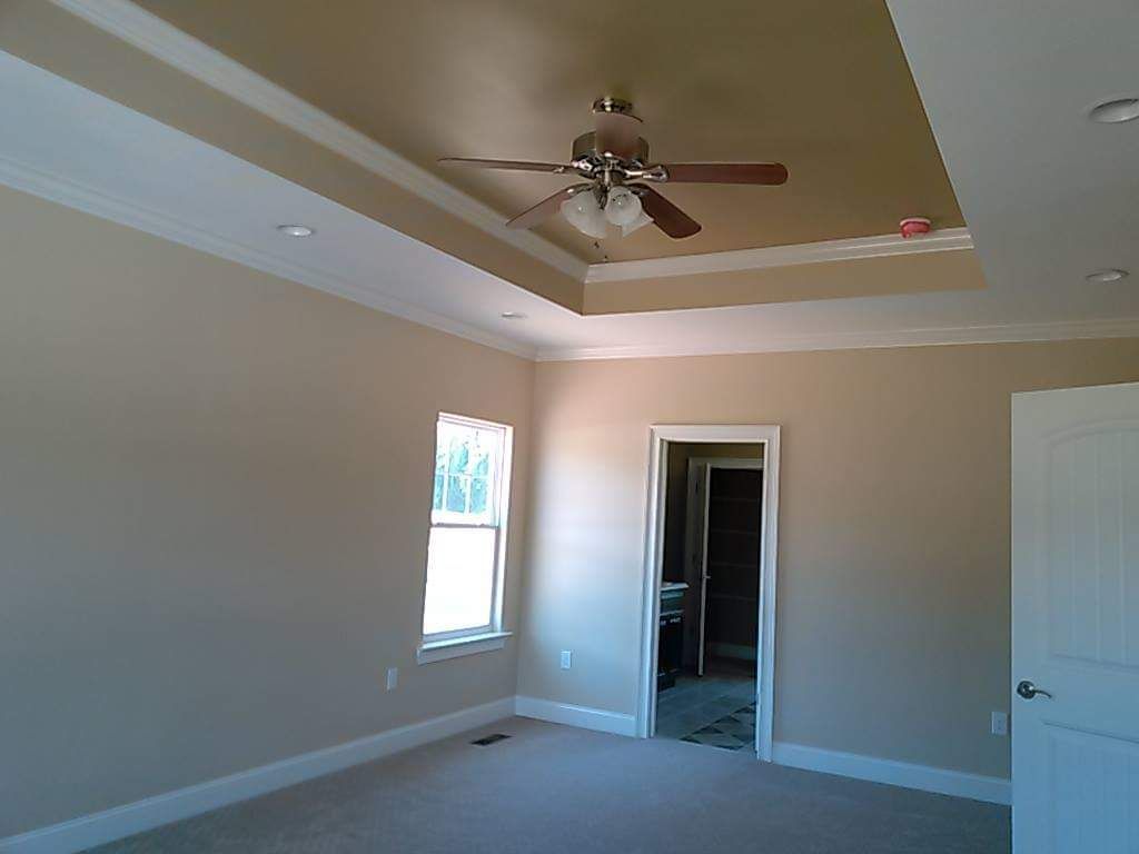 An empty bedroom with a ceiling fan and a window