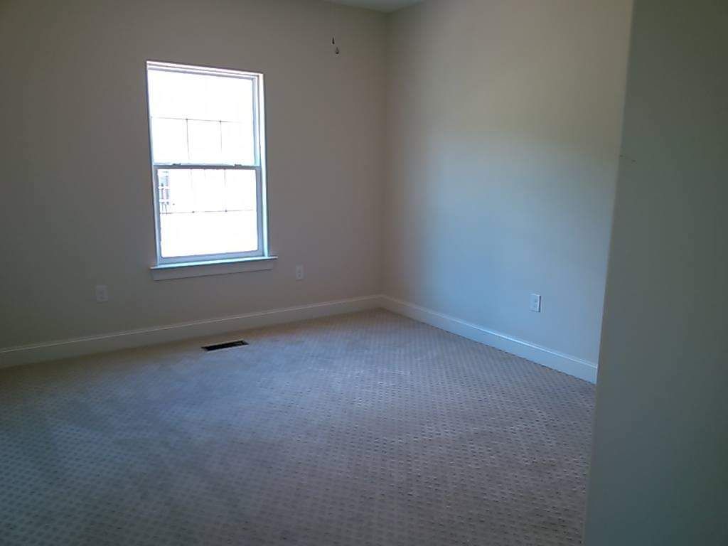 An empty bedroom with a window and a carpeted floor.