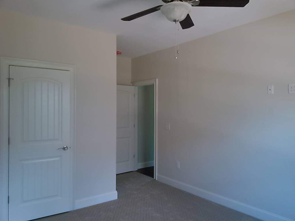 An empty bedroom with a ceiling fan and a door.