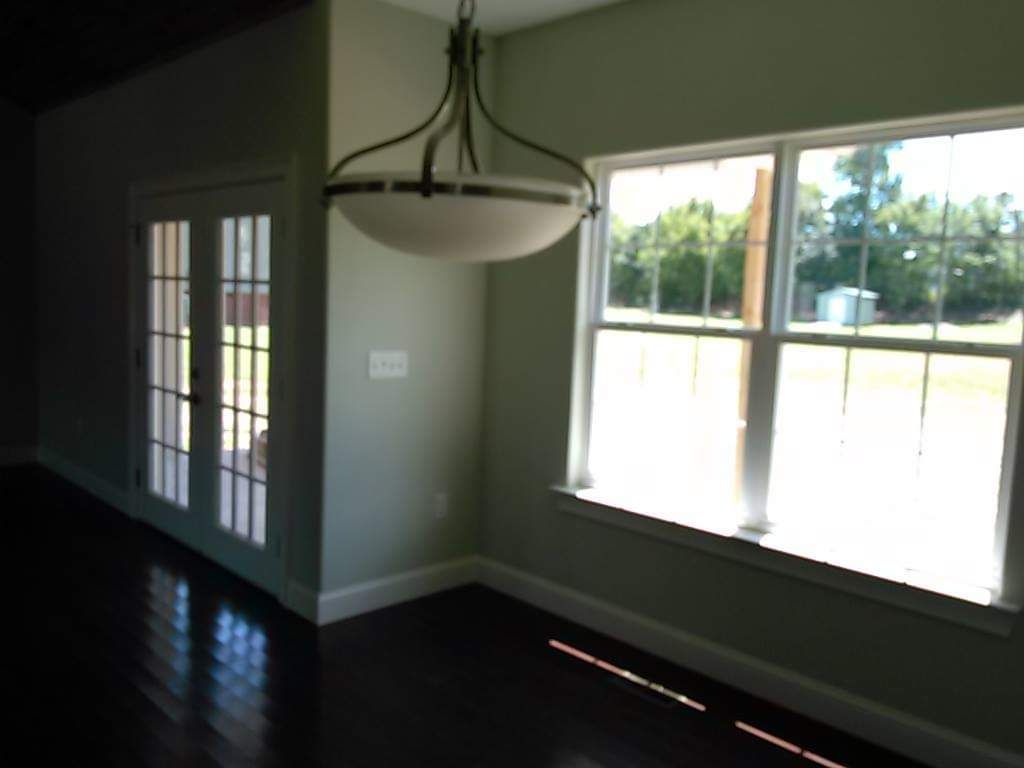 An empty room with a large window and a chandelier hanging from the ceiling