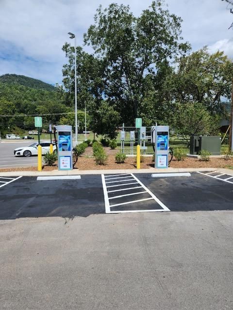 Two charging stations in a parking lot with trees in the background