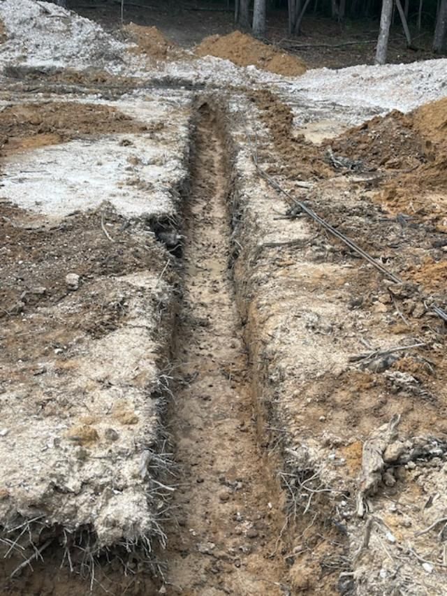 A trench is being dug in the dirt on a construction site.