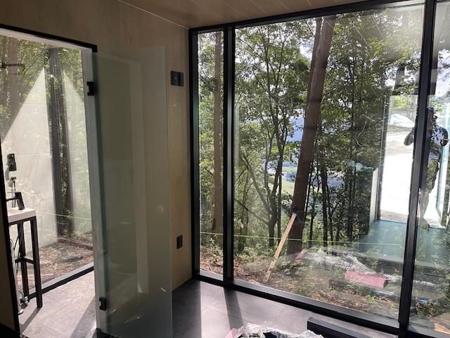 A room with a lot of windows and trees in the background.