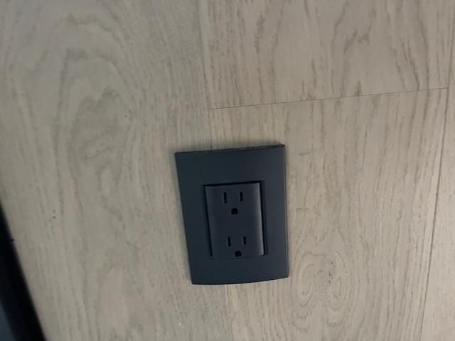 A black electrical outlet is sitting on a wooden floor.