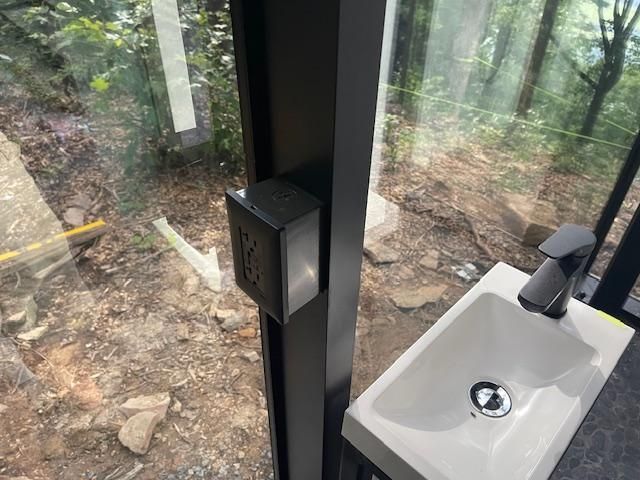A bathroom with a sink and a window with a view of the woods.