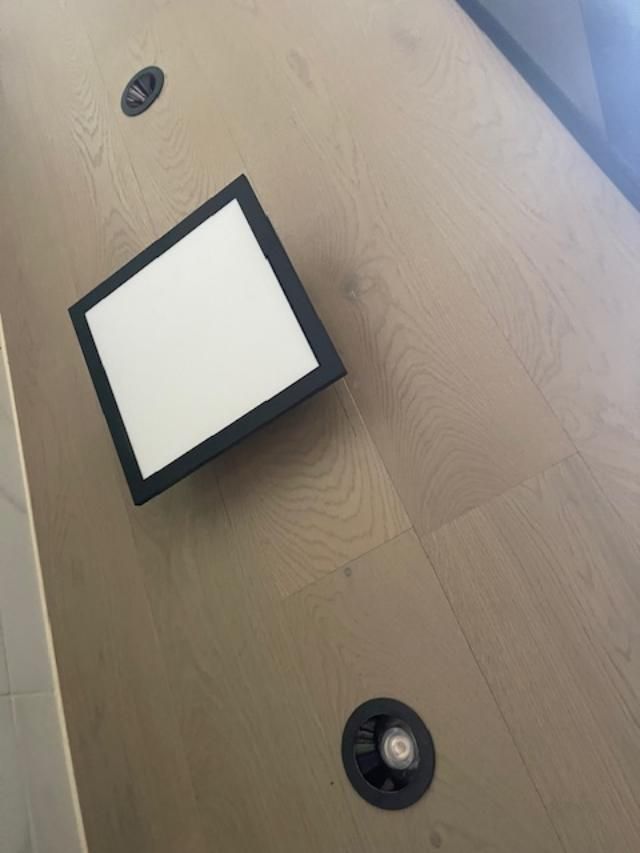 A square light is sitting on top of a wooden floor.
