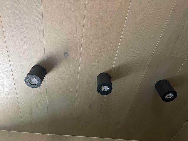 Three black lights are hanging from the ceiling of a wooden room.