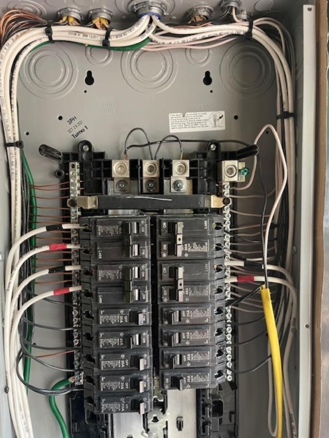 A close up of a electrical panel with a lot of wires coming out of it.