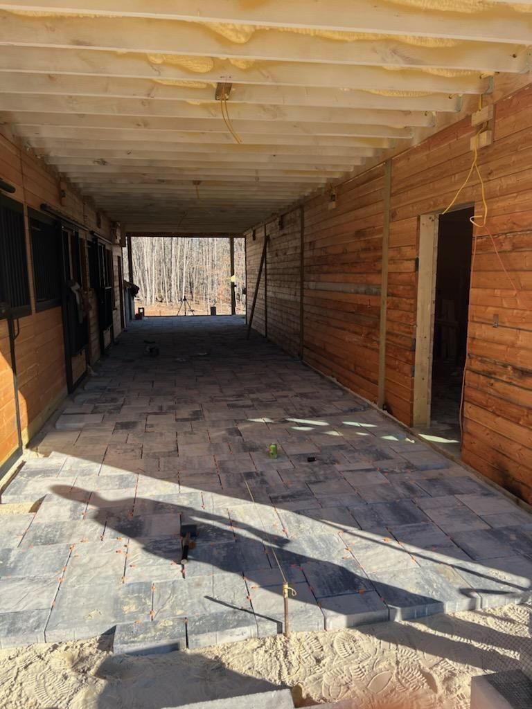 A long hallway between two wooden buildings with a brick floor.