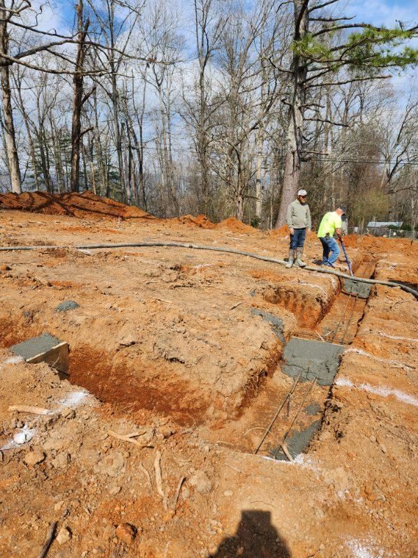 Two construction workers are working on a dirt field.