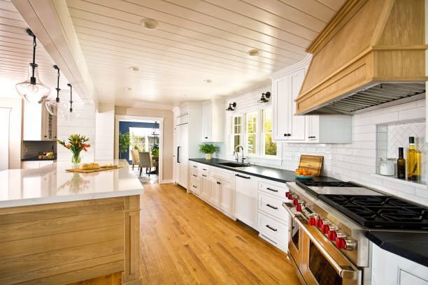 Bright kitchen with white cabinets, wood floor, island, and stainless steel appliances.