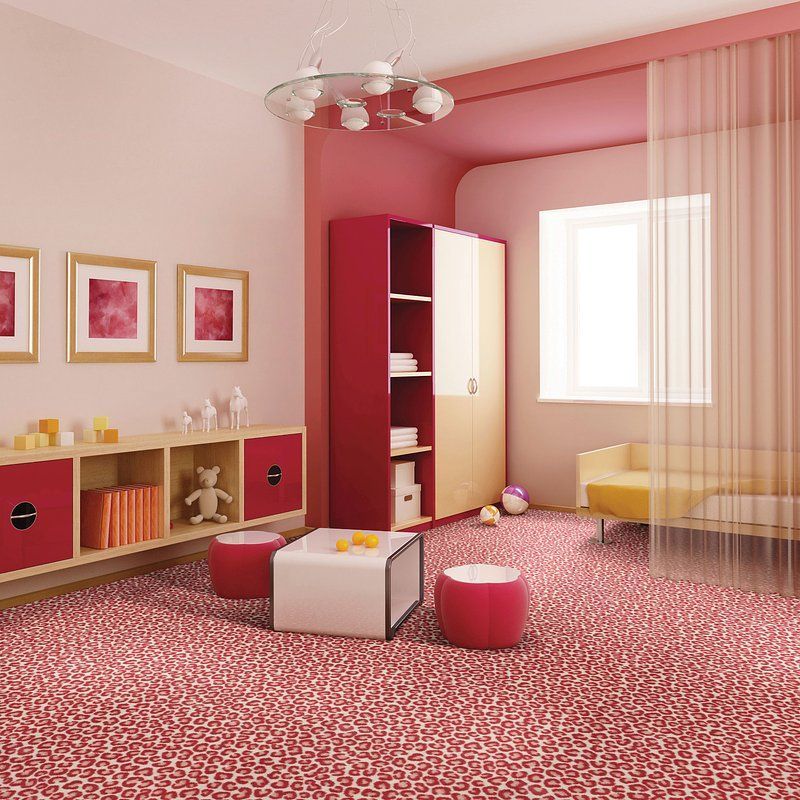 Pink and red children's room with patterned carpet, red cabinets, white table, and small yellow couch near a window.