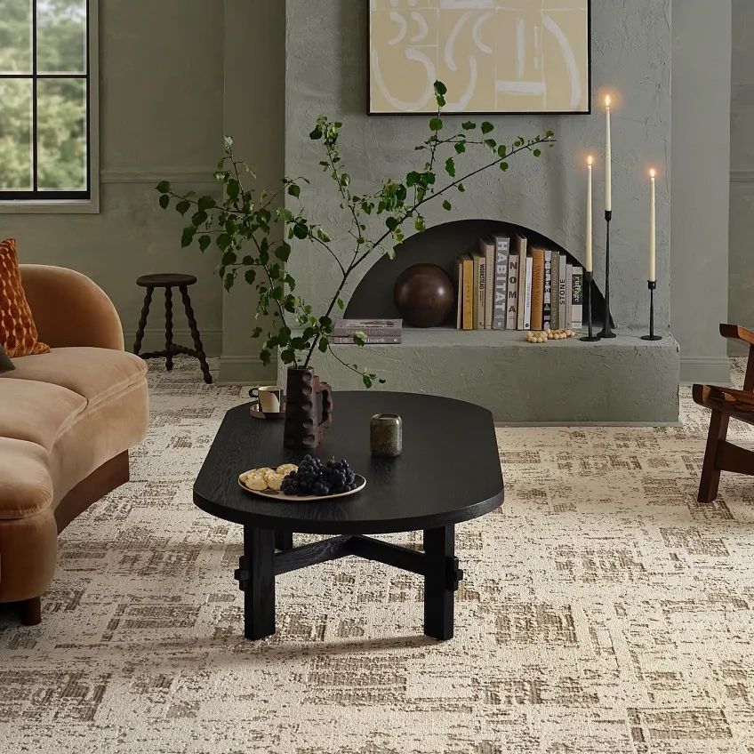 Living room with a patterned rug, curved sofa, dark coffee table, and fireplace.