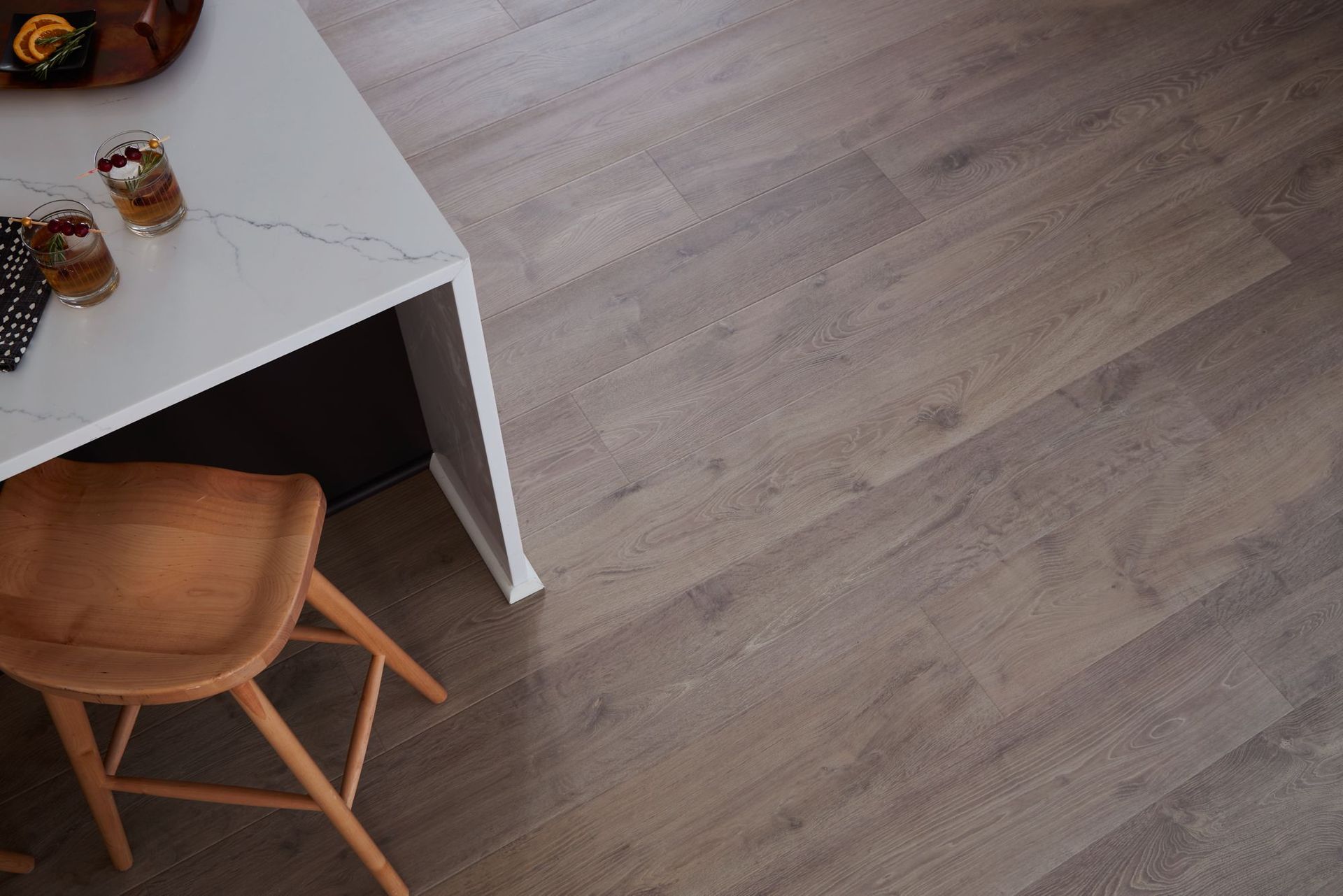 Wooden flooring with a white countertop and a wooden stool.