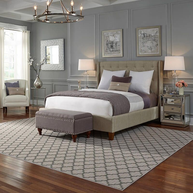 Gray bedroom with a bed, bench, chair, and patterned rug.