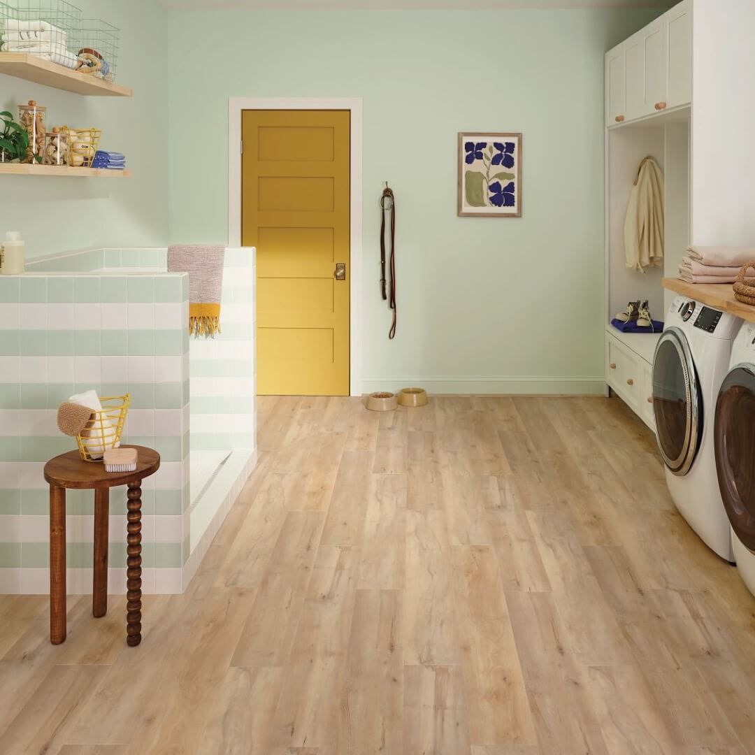 Laundry room with light wood floor, green walls, yellow door, and white appliances.
