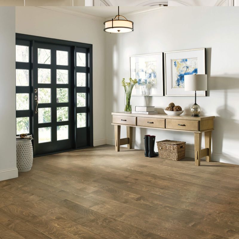 Entryway with wood floors, black door, light wood console table, art, and a hanging light.