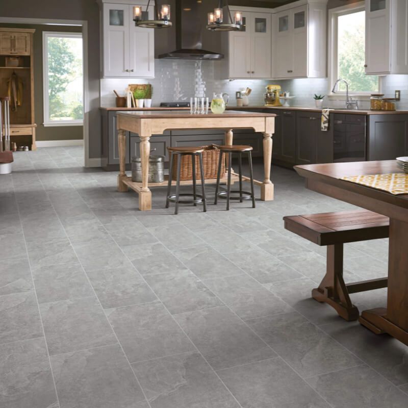 Kitchen with gray tile floor, dark cabinets, and light cabinets. Wooden island and dining table.