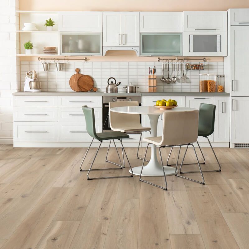 Kitchen with white cabinets, round table, chairs, and light wood flooring.